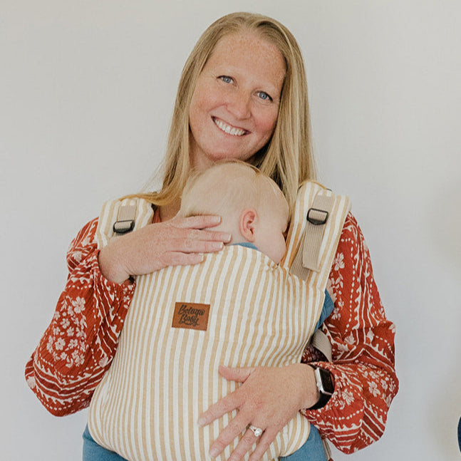 Two women holding children in baby carriers against a white background